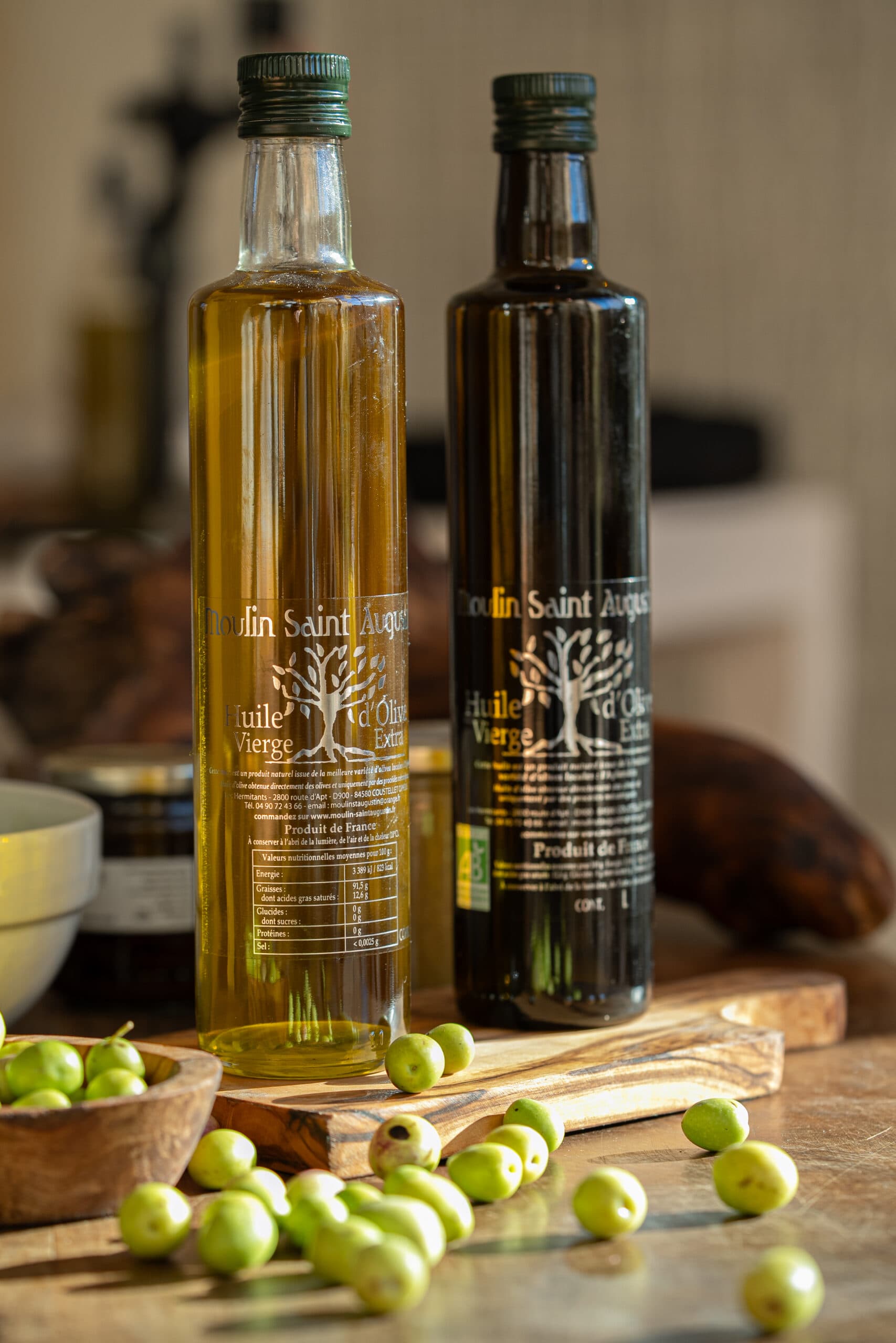 Bouteille d’huile Fruité Mûr posée sur une table en bois, avec des olives